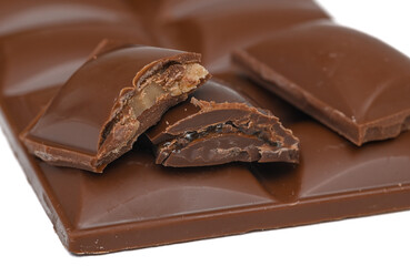 Broken chocolate cubes lying on a chocolate bar, milk chocolate with nougat filling