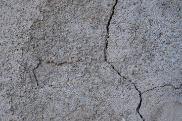 Obraz premium A close - up of a rough, cracked concrete wall with visible fissures