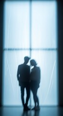 Silhouette of a couple in front of a bright window, a moment of connection.