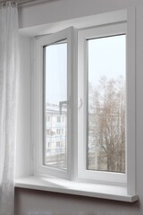 Fototapeta premium Fresh morning light streams through a modern window overlooking a quiet neighborhood in early spring