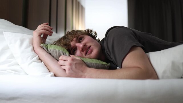 Man lying on bed staring into distance lost in deep thoughts before sleep quiet evening mood calm bedroom atmosphere reflecting insomnia and overthinking in peaceful soft light