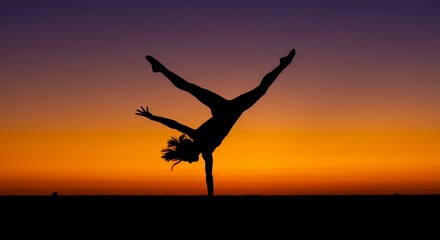 Silhouette of a person performing a handstand against an orange and purple sunset sky