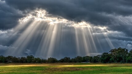 Dramatic Clouds with Sun Rays Shining Over Green Field Landscape Understormy Sky at Dusk