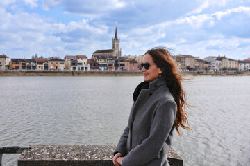 Woman on riverbank with view of Macon city in France