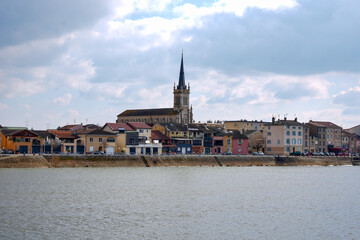 Fototapeta premium Panoramic cityscape of Macon France with historic church and colorful buildings along the Saone River under cloudy sky