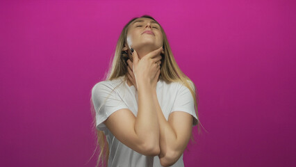 Woman choking holds neck wearing white shirt against pink background expressing discomfort health concept.