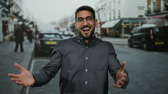 Smiling young man with glasses standing on a busy urban street showcasing joy in an outdoor city setting.