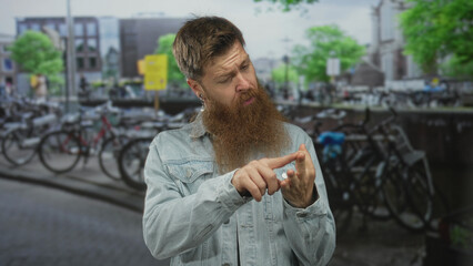 Fototapeta premium Man pointing finger to palm in bike rental parking on urban street, denim jacket visible; concentration.