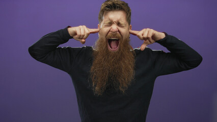 Man with long red beard covers ears with fingers and closes his eyes in studio; mental overload...