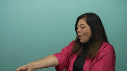 Fototapeta premium Woman pulls a thick woven rope with outstretched arm in teal studio; determination effort perseverance