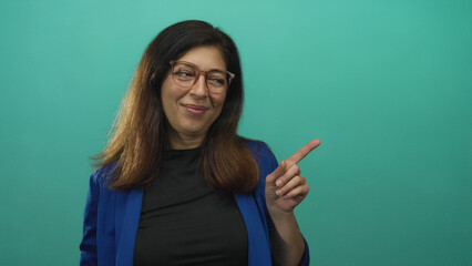 Woman finger raised in call me gesture and pointing finger to the side in teal studio; friendly invitation.