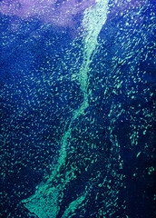 Bioluminescent water forming an abstract stream pattern, creating a vivid texture of glowing teal and electric blue colors in a fluid, deep sea like environment