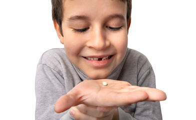 Obraz premium Happy little boy holds a fallen baby tooth symbolizing the hygiene of baby teeth. Hand showing first tooth lost reflecting child's development. Children show teeth new gap, dentist problems