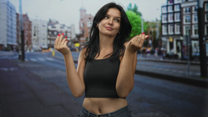 Young hispanic woman wearing black crop top shows pinched fingers money gesture on city street with...