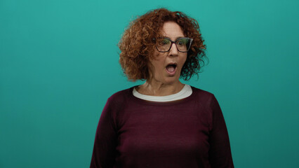 Woman with curly hair and glasses expressing surprise against a vibrant green background, evoking...