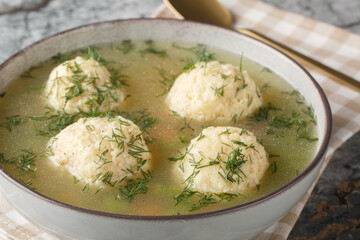 Jewish matzah balls soup with chicken broth, vegetables and dill close-up in a plate on the table. Horizontal