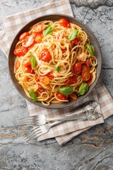 Pasta Margherita with fresh tomatoes, mozzarella cheese, basil and olive oil close-up in a plate on the table. Vertical top view from above