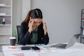 Upset and tired asian woman sitting at workplace inside office, business woman leaning on arms...