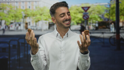 Man holding cookies with both hands in white shirt on bustling city street with blurred...