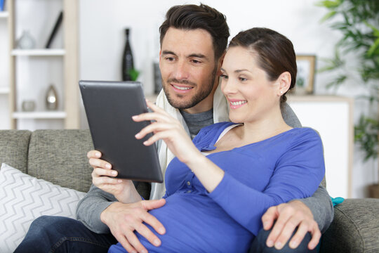 couple with pregnant woman looking at tablet