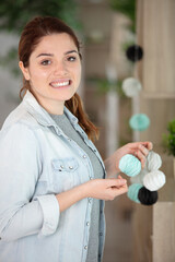 young woman decorator hanging up paper garlands