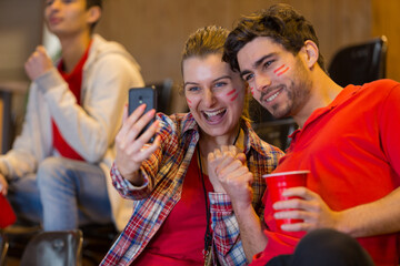 group of sport supporters at stadium taking selfie