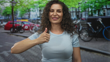 Woman pointing finger to chest in light blue shirt on busy urban street with bicycles and cars; confidence.