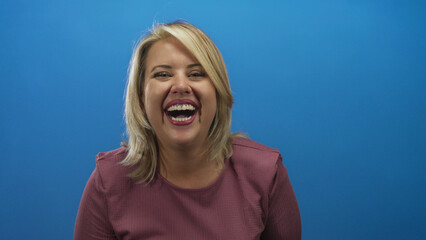 Blonde woman wearing pink sweater laughs and smiles broadly while pointing finger at camera in...