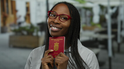 Woman holding danish passport outdoors at terrace cafe smiling confidently in casual setting with...
