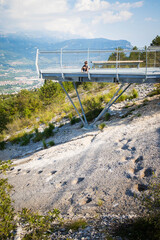 Child boy visiting the dinosaur fossil footprints site located in Rovereto, Trentino, Italy. The kid is looking the ancient tracks from a platform above the rock. Vertical shot.