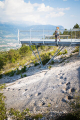 Two kids visiting the dinosaur fossil footprints site located in Rovereto, Trentino, Italy. The children are looking the ancient tracks from a platform above the rock. Vertical shot.