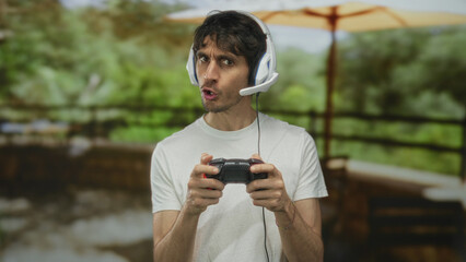 Man wearing white headset holds black game controller with intense gaze and surprised expression in...