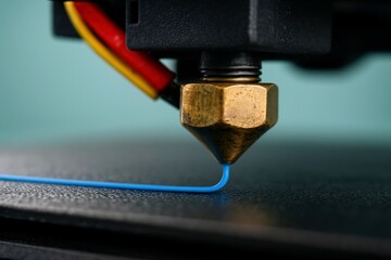 3D printer nozzle precisely extrudes vibrant blue filament, meticulously layering plastic material onto the build plate, symbolizing modern innovation and advanced manufacturing technology