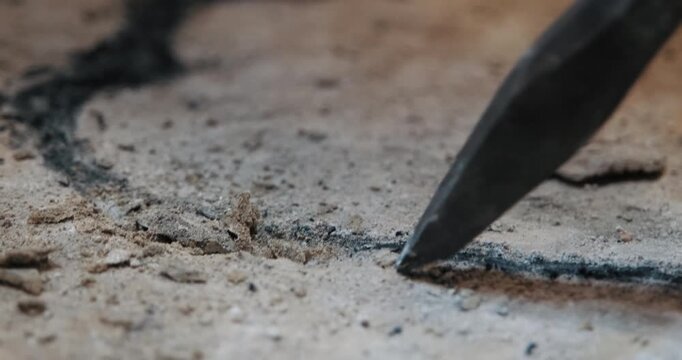 Extreme close-up (macro) shot of a chisel tip carving along a line on stone. (Sound On) Clear hammer strikes chip away particles. Precision craft and historical stonemasonry.