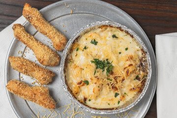 Pasta dish topped with cheese and herbs, served with golden garlic breadsticks.