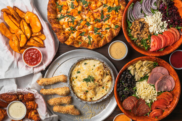 Assorted meal spread with pizza, salad, wings, and pasta