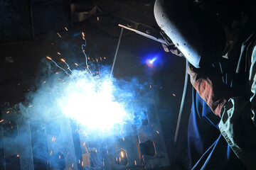 Industrial Welding Process with Bright Sparks and Blue Flame
