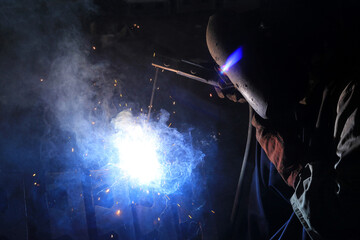 Industrial Welding Process with Bright Sparks and Blue Flame