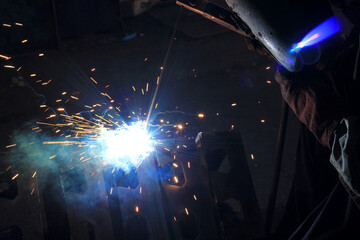 Industrial Welding Process with Bright Sparks and Blue Flame