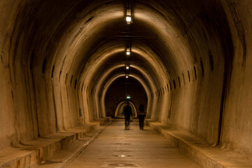 Zagreb, Croatia - August 23, 2024: Illuminated underground tunnel in Zagreb with arched concrete walls and a long perspective view leading toward distant figures.