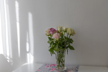 Pastel colored roses in a vase on a table