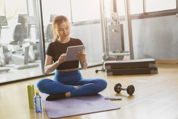sport healthy asian women sitting in gym fitness using tablet, learning online sports training