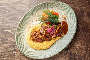 Gourmet dish with creamy polenta, mushroom stew, shredded meat, roasted vegetables, and fresh herbs on ceramic plate. Rustic presentation, ideal for food photography.