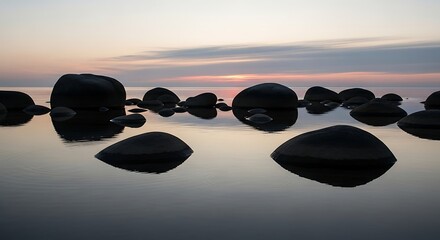 Smooth stones on calm water at sunset