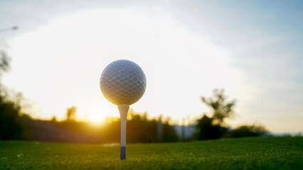 Close-up golf ball on tee with blur green bokeh background.
