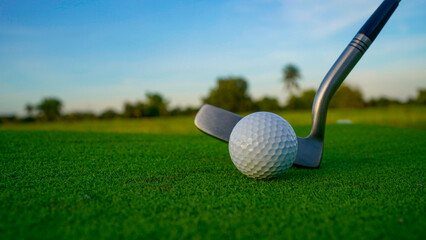 Golf clubs and balls on a green lawn in a beautiful golf course with morning sunshine.