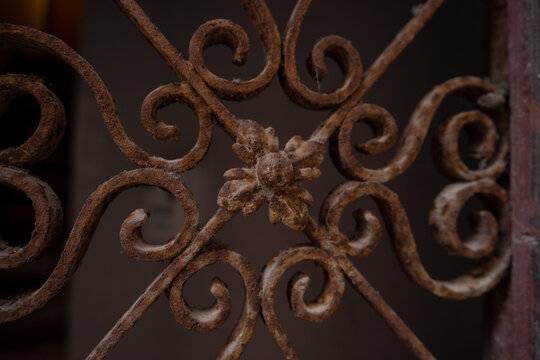 Rovinj, Croatia - August 15, 2025: Close-up of an ornate rusted wrought iron pattern in Rovinj, showing intricate scrolls and a small floral detail in the center.