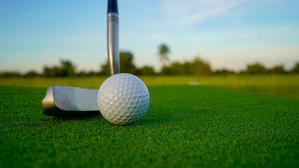 Golf clubs and balls on a green lawn in a beautiful golf course with morning sunshine.
