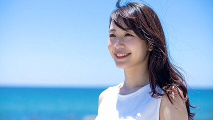 快晴の海辺で微笑む若い女性 素材 16:9サイズ AI生成素材