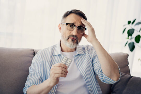 Concerned mature man at home holding medication and portraying health awareness and thoughtful reflection - Powered by Adobe